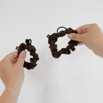 two dark brown scrunchies held up