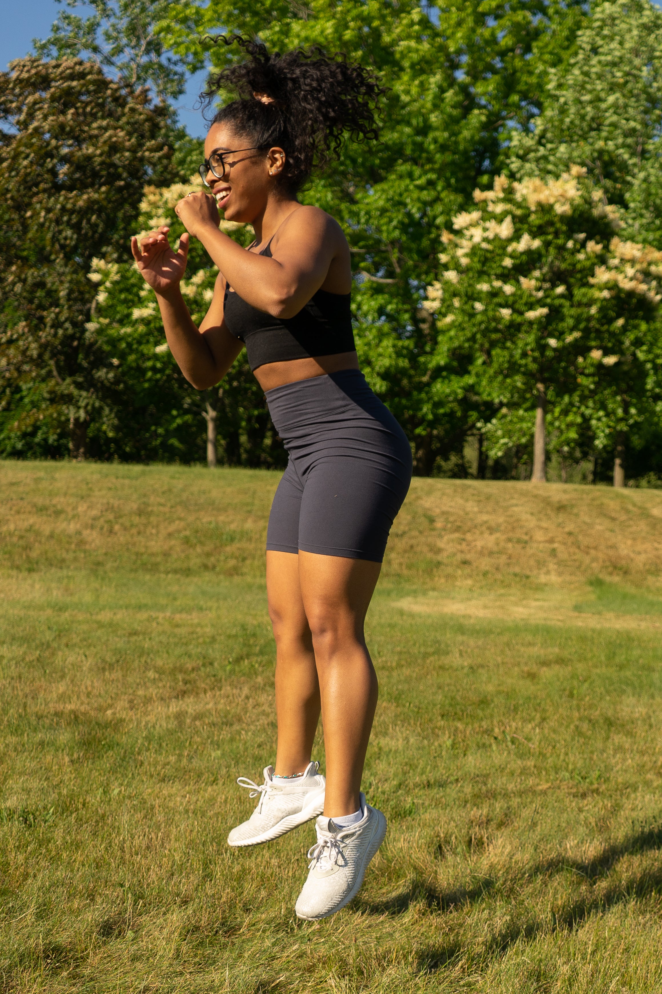 Women with curly hair jumping and wearing a hairstrong scrunchie in a high ponytail 