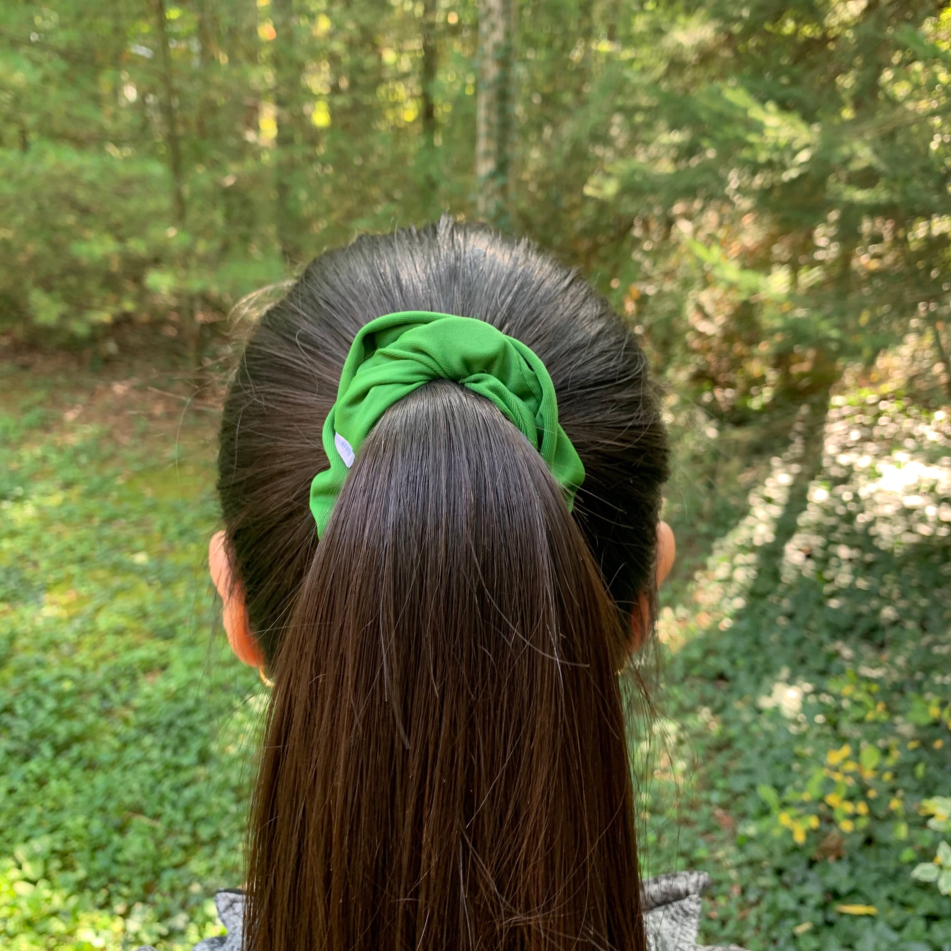 Women with dark brown hair in an olive scrunchie
